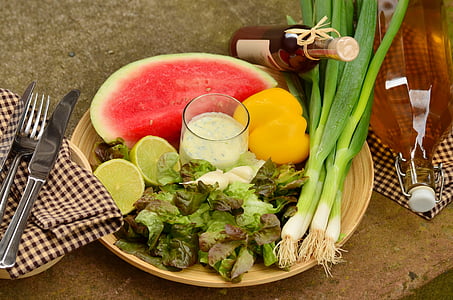 vegetable salad with slice of watermelon on plate beside knife and fork thumbnail