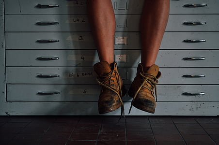 person wearing brown boots sitting on filing cabinet thumbnail