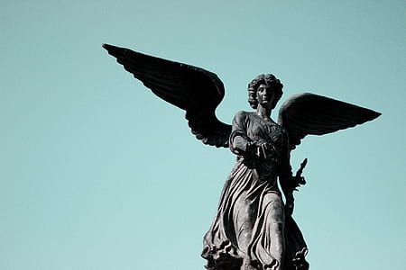 statue of woman wearing dress with wings under blue sky thumbnail