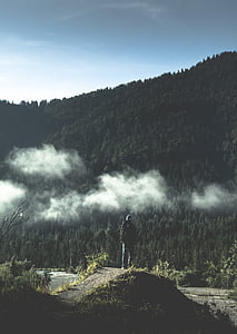 person standing on pathway facing in front of mountain thumbnail