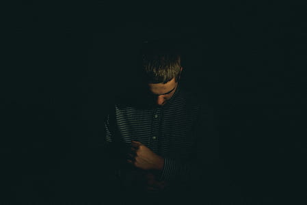 man looking down while holding his clothes sleeves thumbnail