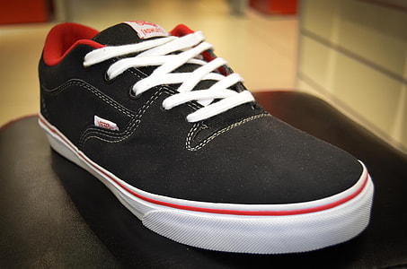 unpaired black and red Vans off the Wall low-top sneaker on black surface thumbnail