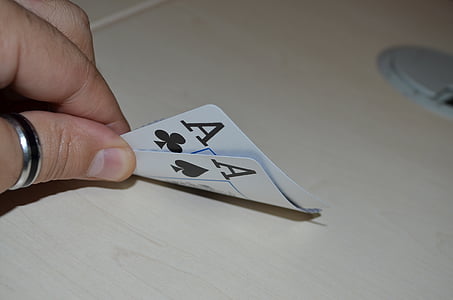 person holding two Ace of Clubs and Spades playing cards thumbnail