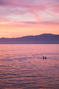 two people floating on calm water during golden hour thumbnail