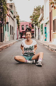 girl sitting on road while taking her tongue out thumbnail