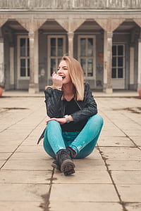 woman sitting while laughing on gray pavement thumbnail