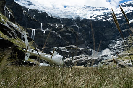 grass field overlooking snow covered mountain thumbnail