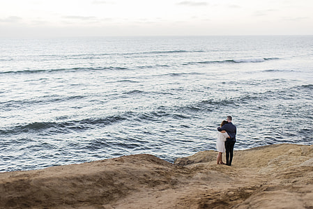 couple standing near body of water under blue sky at daytime thumbnail