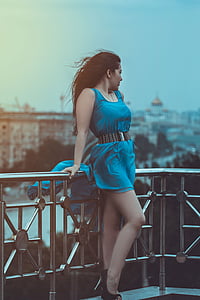 woman wearing blue scoop-neck sleeveless mini dress leaning on terrace while looking left thumbnail