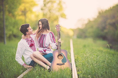 man in white-and-pink long-sleeved shirt carrying woman in dress holding guitar thumbnail
