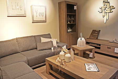 gray sectional sofa with rectangular brown wooden coffee table and assorted ornaments on top inside white painted room thumbnail
