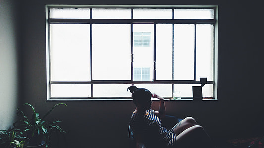 woman wearing white and blue striped shirt sitting on chair near window thumbnail