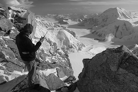 grayscale photography of man standing near cliff thumbnail
