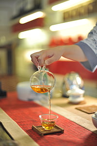 selective focus photo of person holding pitcher pouring tea into cup thumbnail