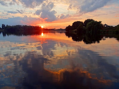trees across body of water in panoramic view photography during golden hour thumbnail