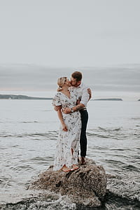 man and woman kissing on top of rock at beach thumbnail