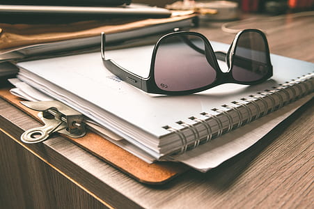 Black Frame Wayfarer Sunglasses on White Notebook thumbnail