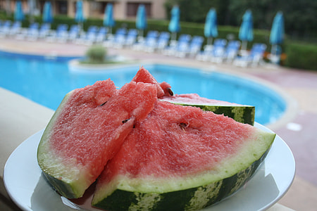 sliced watermelons on plate near in-ground pool thumbnail