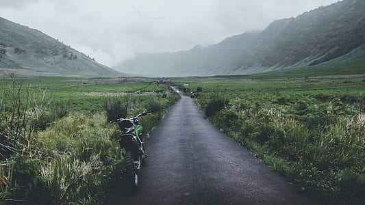 green motorcycle near grassland during daytime thumbnail