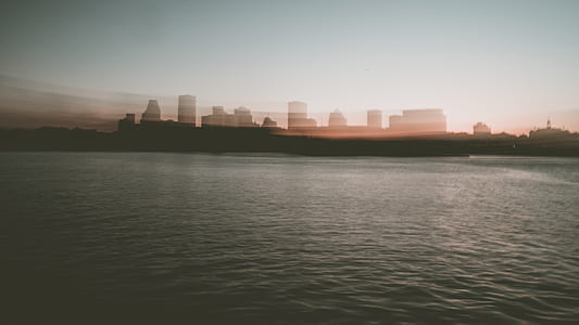 silhouette of city between sky and body of water thumbnail