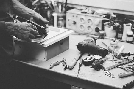 greyscale photo of man with work tools on top of table thumbnail