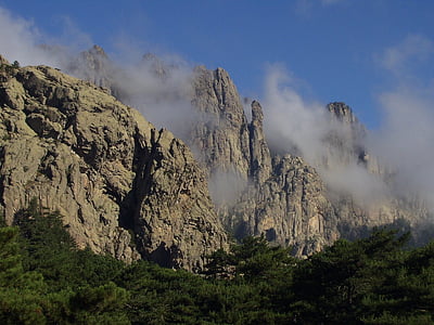 gray rocky mountain with fogs and trees during daytime photography thumbnail