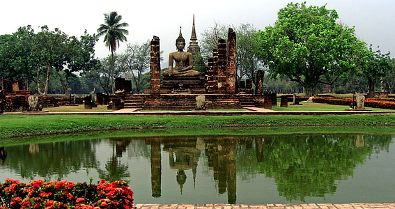 photo of Gautama Buddha statue between trees and near body of water thumbnail