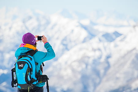 man taking photo of snow-covered mountain range thumbnail