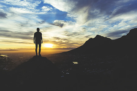 silhouette photography of man standing on cliff during golden hour thumbnail