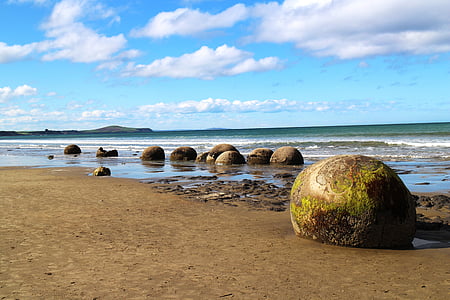 medium rocks on shoreline under white and blue cloudy sky at daytime thumbnail