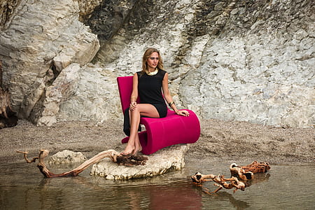 woman sitting on pink chair near gray mountain thumbnail
