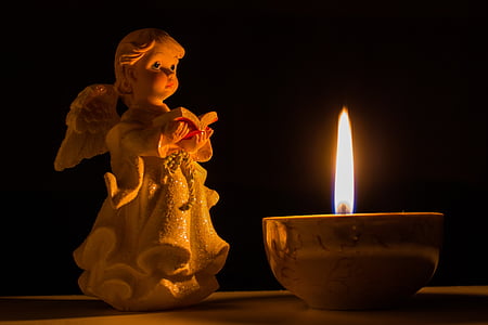 angel holding book figurine beside lighted candle thumbnail