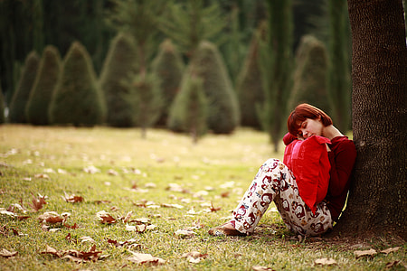 woman holding pillow leaning on tree photo thumbnail