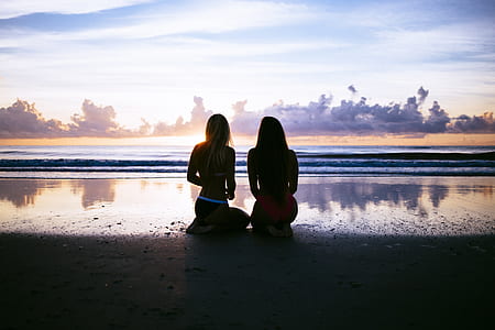 silhouette of two women sitting at seashore thumbnail