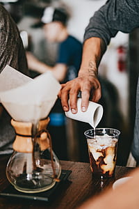 man pouring milk on clear plastic cup thumbnail