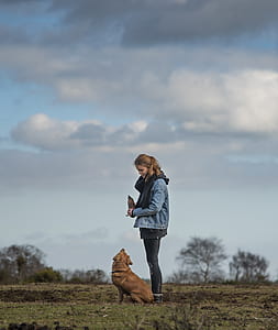 woman standing beside short-coated brown dog during cloudy day thumbnail