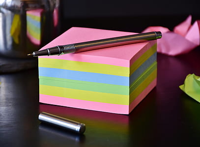 shallow focus photography of brown ballpoint pen on pink and green box thumbnail