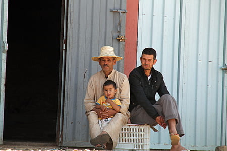 three male seating on white crate thumbnail