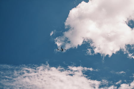 airplane flying under cloudy sky thumbnail