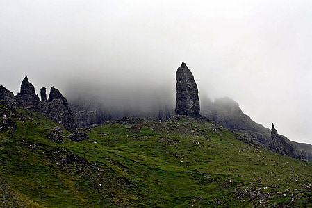 rock formations in green grass field under cloudy sky during daytime thumbnail