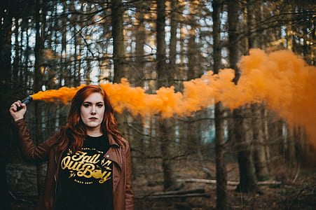 woman holding orange flare on forest thumbnail
