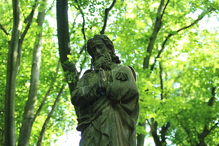 praying man statue surrounded by trees thumbnail