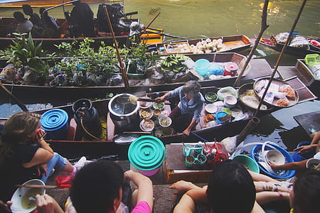woman on boat surrounded by variety of cooked food thumbnail