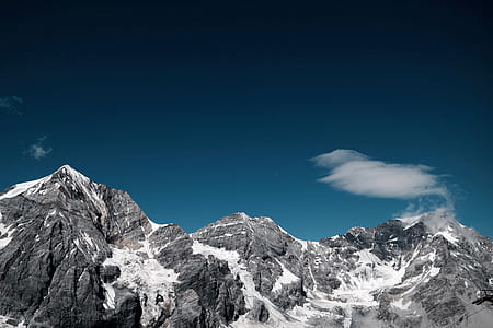 gray rock formation covered by snow under the blue sky thumbnail