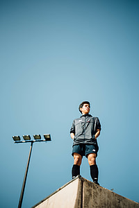 man in black zip-up shirt and blue shirts standing on top of building under clear blue sky during daytime thumbnail