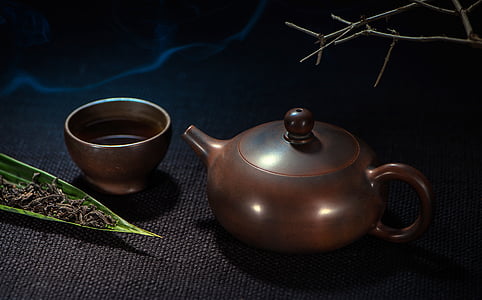brown teapot near cup on black surface thumbnail