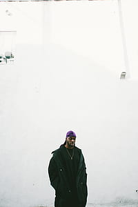man standing near white concrete wall during daytime thumbnail