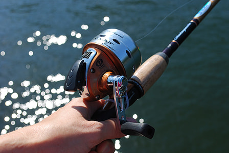 person holding black and gray fishing rod with reel thumbnail