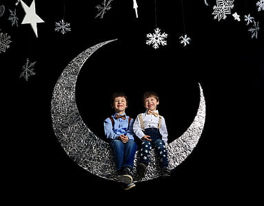 two boys sitting on silver moon hanging decor thumbnail