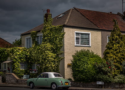 classic yellow coupe parked beside brown house thumbnail